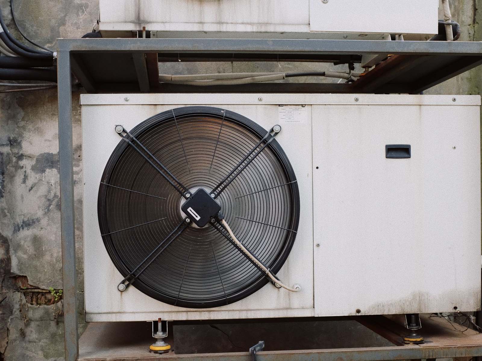 Condensing units on a steel rack against an old brick wall