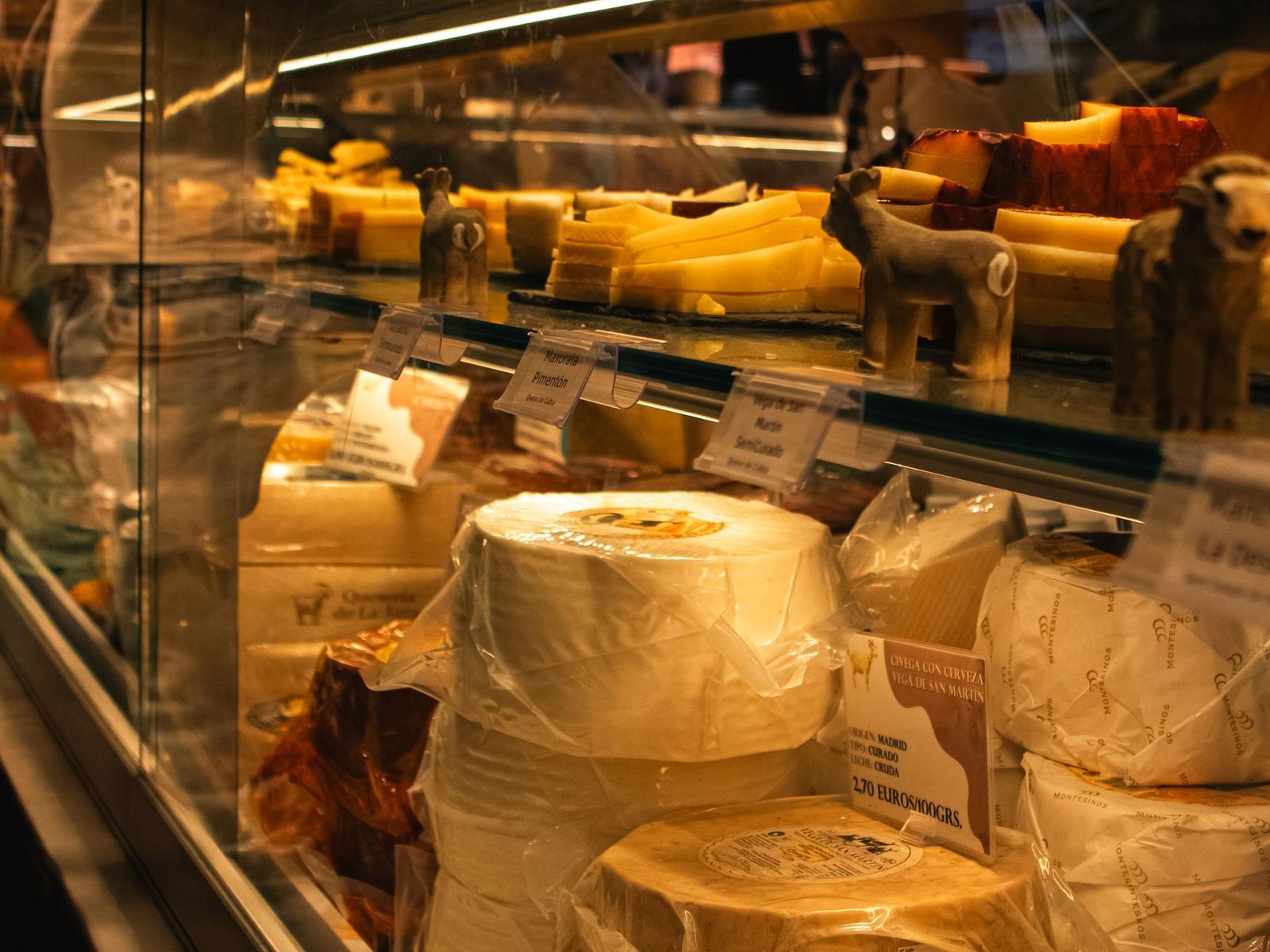 Refrigerated deli display case with cheese behind glass