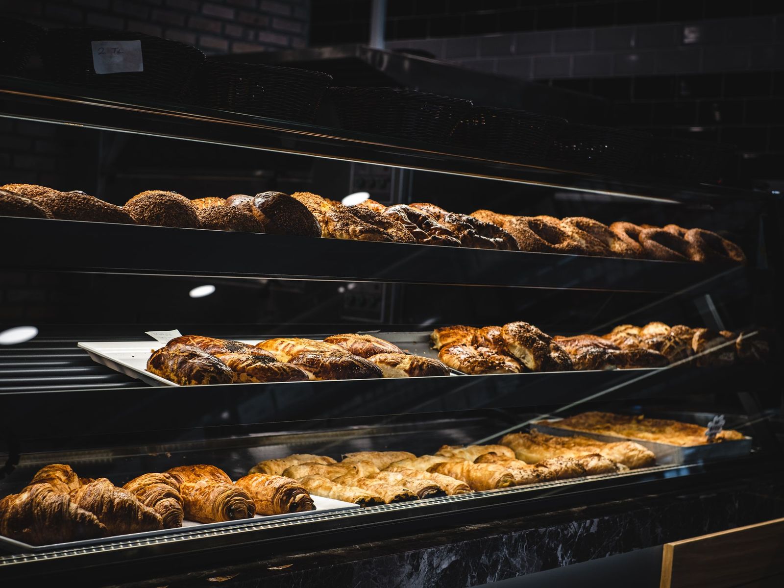 Pastries on shelves in a lit bakery display case