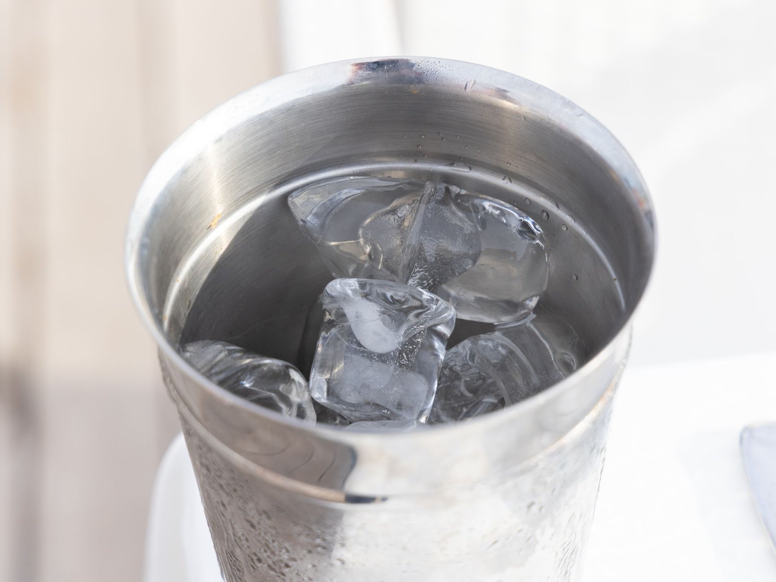 Ice in a stainless steel cup on a bar counter