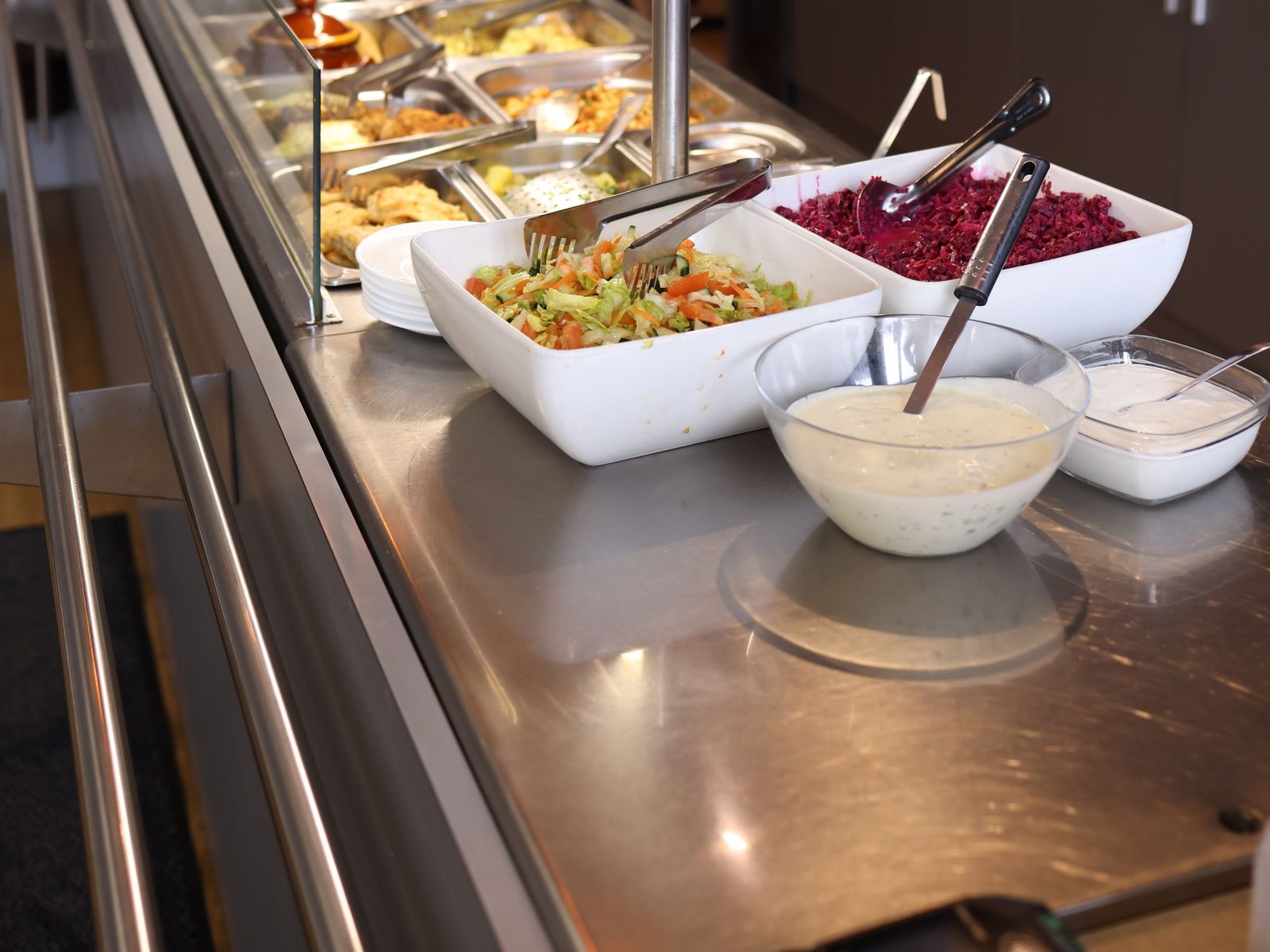 Cafeteria serving line with salads and hot food wells