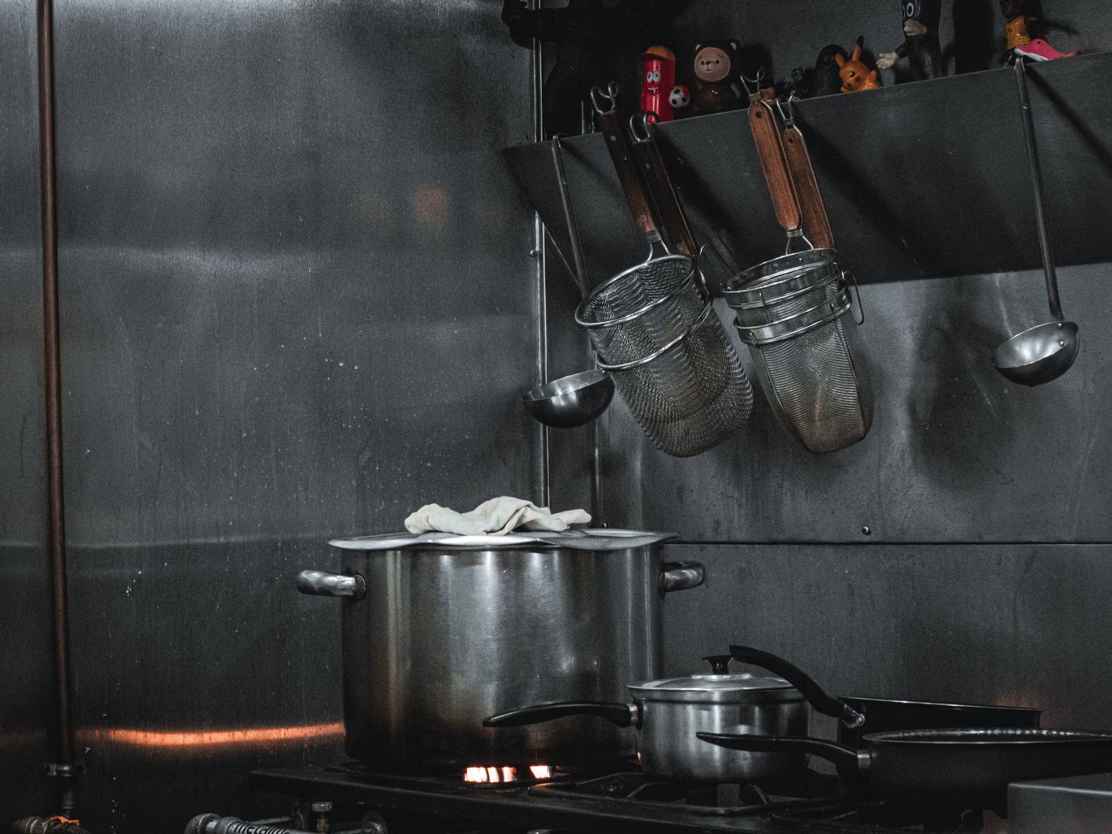 Pots on the range under a rack of strainers in a restaurant kitchen