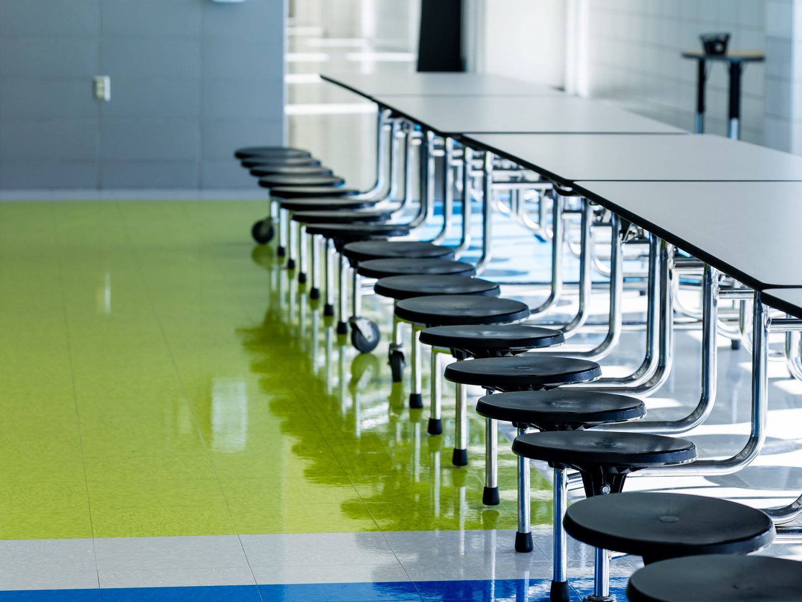 Empty school cafeteria with long tables and stools